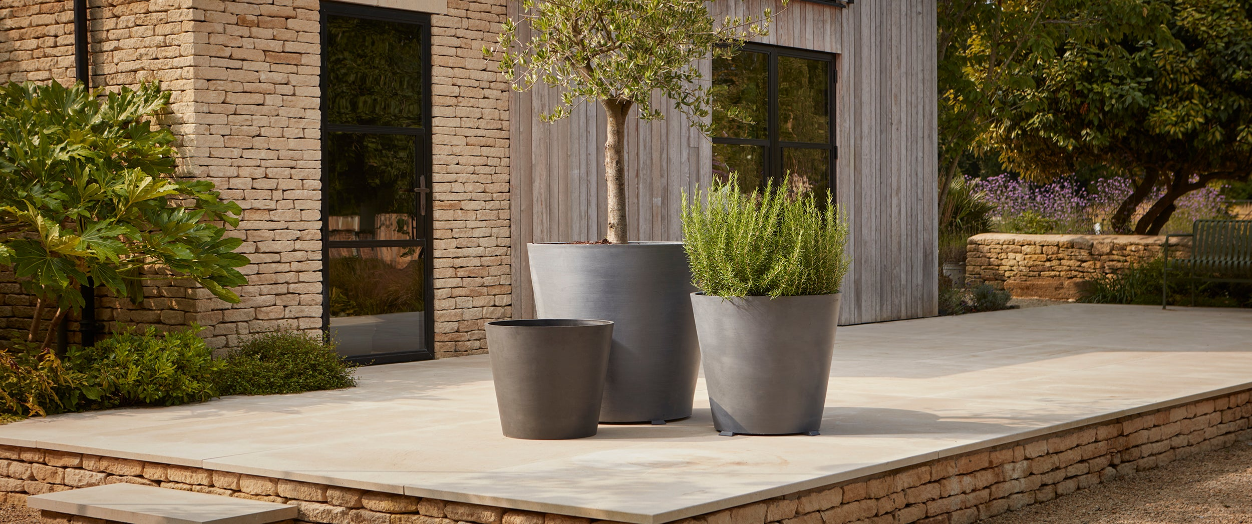 A collection of tieless, sustainable recycled plastic plant pots on wheels, black, charcoal, anthracite and grey 