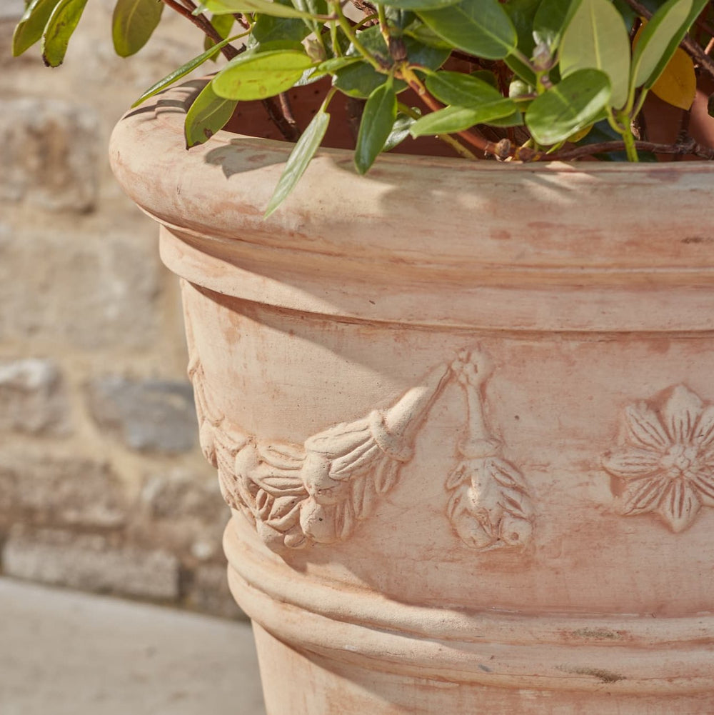 Close-up of the rim of the Lena Terracotta Pot, showcasing the detailed floral garland design and the soft, slightly weathered texture of the clay, emphasizing the artisanal craftsmanship.