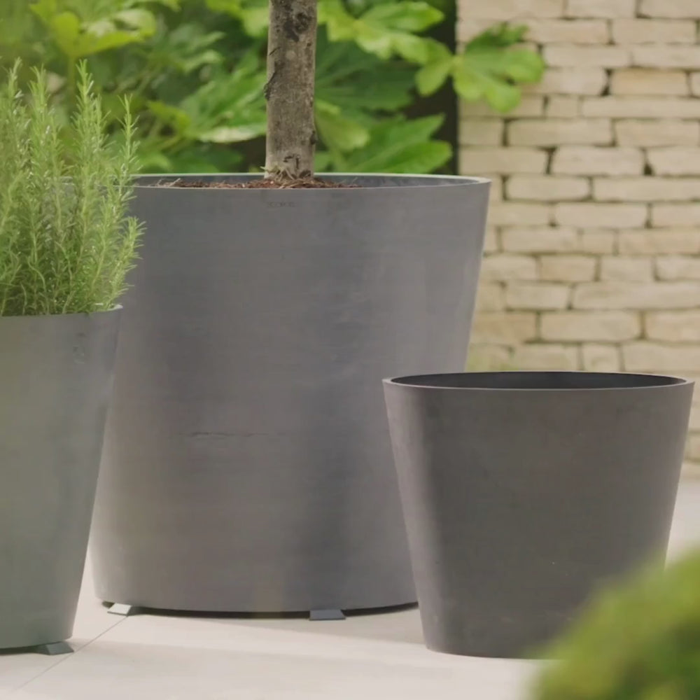 Set of tall grey metal planters displayed outside a contemporary home, ideal for statement trees and outdoor greenery.