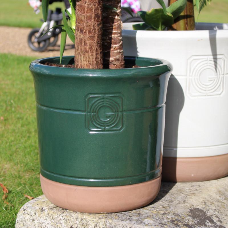 A detailed view of the green glazed planter with embossed detailing, showcasing its smooth finish and terracotta base.