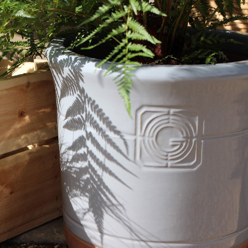 A detailed view of the planter’s embossed design and glossy white glaze, highlighting its smooth finish and terracotta contrast.